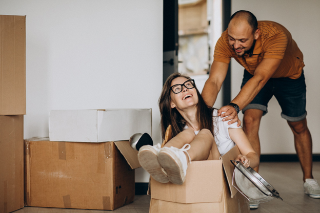 Happy middle-aged couple having fun while moving into a new home surrounded by boxes — symbolizing reinvention and fresh starts in midlife.
